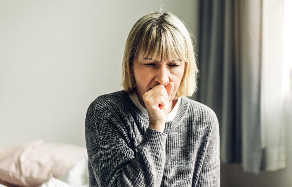 woman coughing into fist